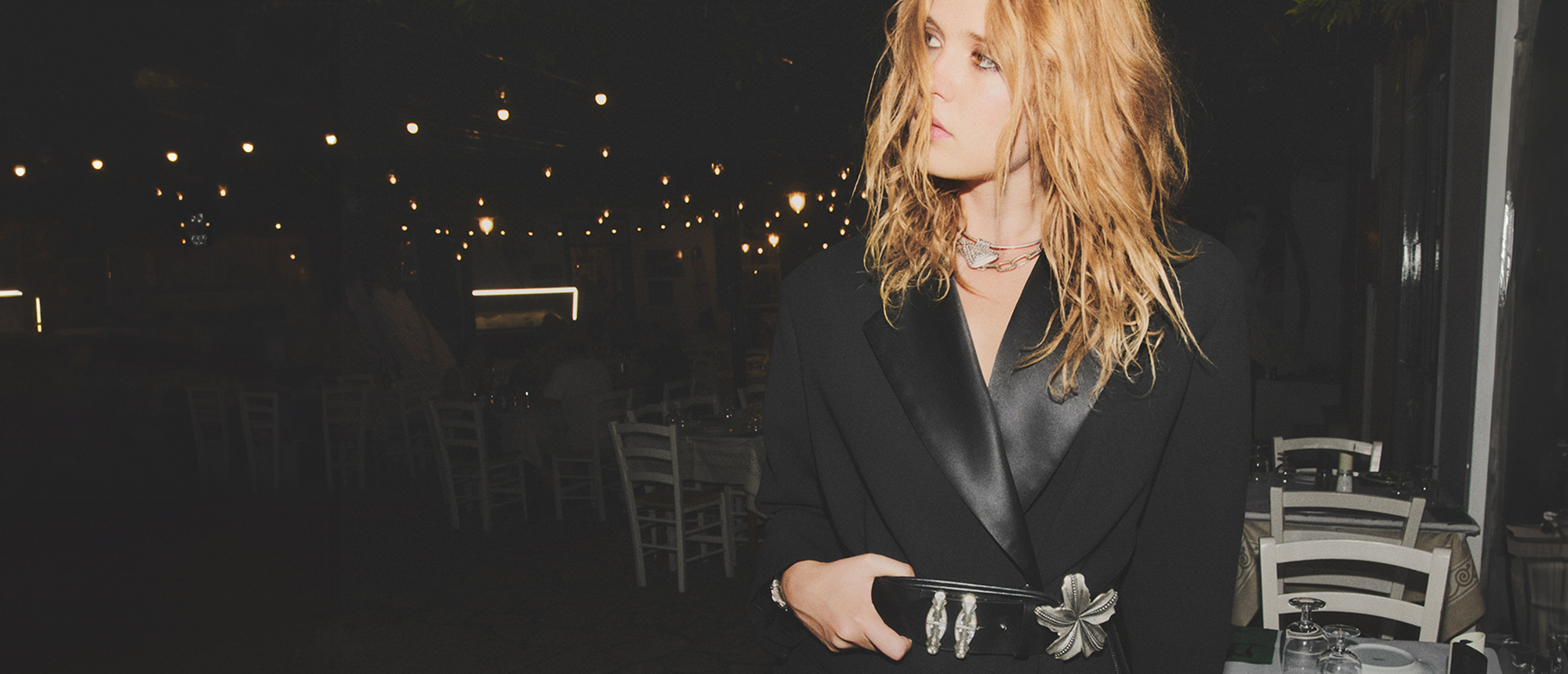 A blonde model wearing a black blazer with a black and silver belt 